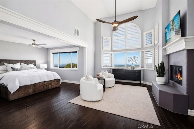 bedroom with dark wood-style floors, multiple windows, a glass covered fireplace, and visible vents