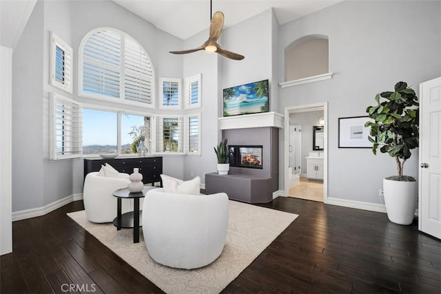 living room featuring dark wood-style flooring, baseboards, and a multi sided fireplace