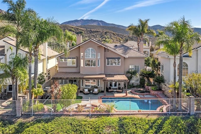 back of house with a patio, fence, a mountain view, and stucco siding