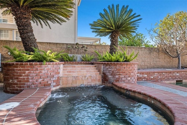 view of swimming pool with an in ground hot tub and fence