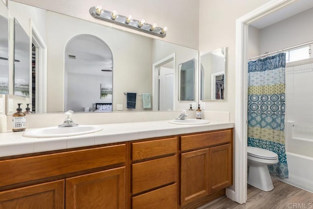 bathroom with double vanity, a sink, toilet, and shower / tub combo with curtain