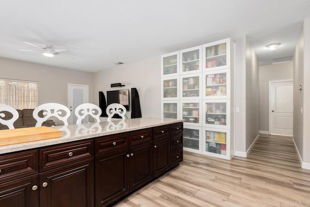 kitchen with dark brown cabinetry, visible vents, baseboards, light wood-style flooring, and ceiling fan