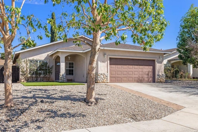 ranch-style house with driveway, fence, an attached garage, and stucco siding