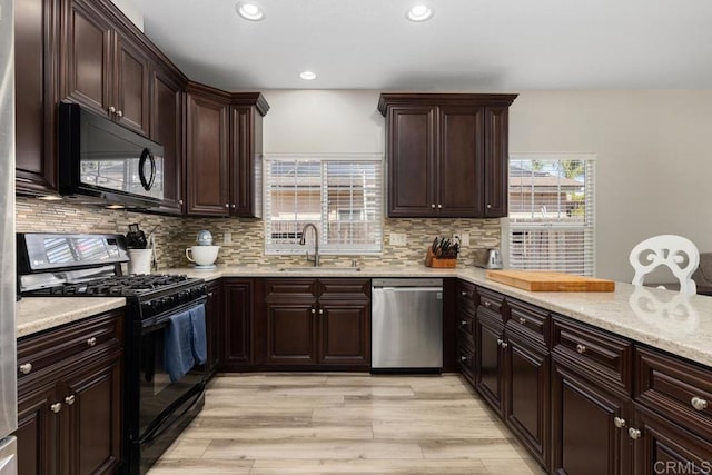 kitchen with recessed lighting, light wood-style flooring, backsplash, a sink, and black appliances