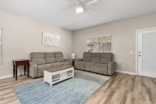 living area featuring a ceiling fan, baseboards, and wood finished floors