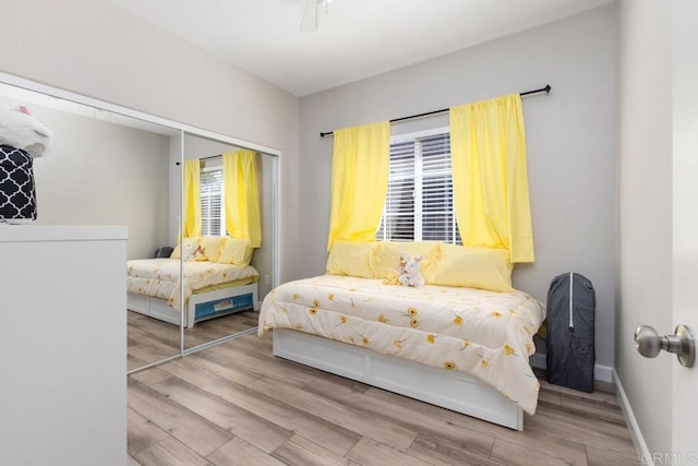 bedroom with a ceiling fan, baseboards, a closet, and wood finished floors