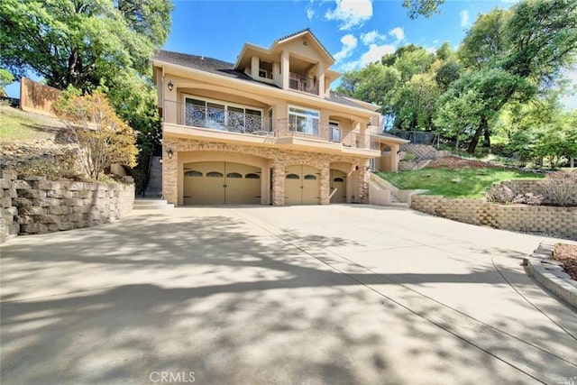 view of front of property with a garage, concrete driveway, a balcony, and stucco siding