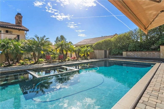 view of swimming pool with a fenced backyard and a pool with connected hot tub