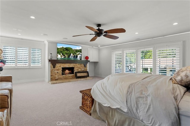 bedroom with multiple windows, a fireplace, light carpet, and baseboards