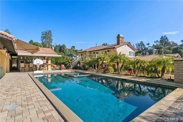 pool featuring exterior bar, stairs, and a patio