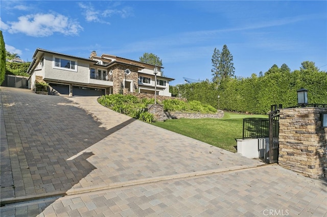 view of front of house with a garage, stone siding, decorative driveway, a front yard, and stucco siding