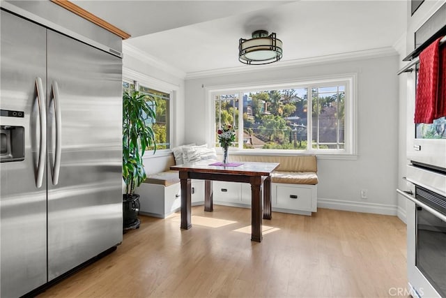 kitchen featuring breakfast area, light wood-type flooring, ornamental molding, and built in refrigerator