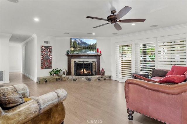 living room featuring a stone fireplace, ornamental molding, and visible vents