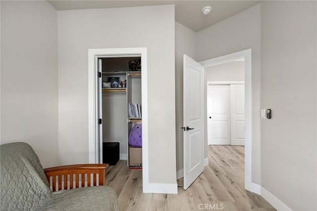 bedroom featuring light wood finished floors, baseboards, a walk in closet, and a closet