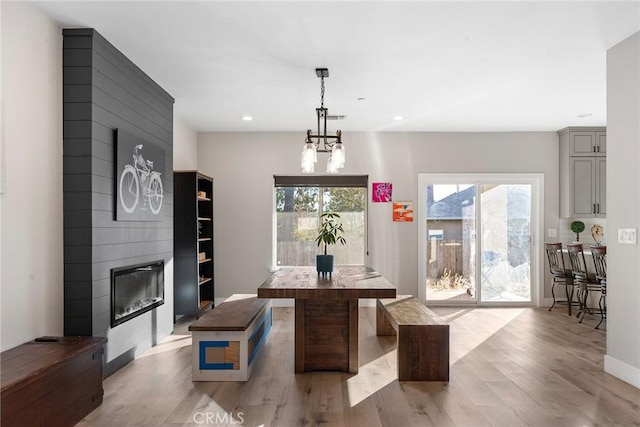 dining space featuring light wood finished floors, baseboards, a fireplace, a notable chandelier, and recessed lighting