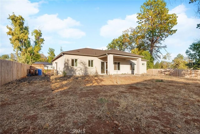 back of property with a fenced backyard and stucco siding