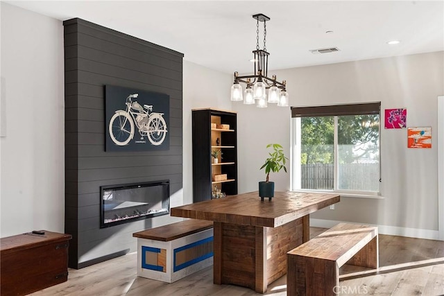 dining area with light wood-style flooring, a fireplace, visible vents, and baseboards