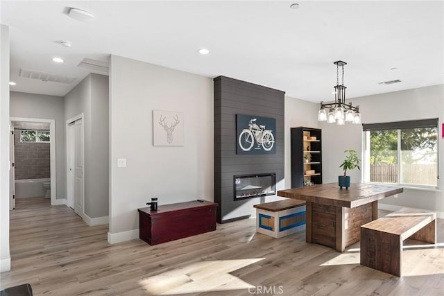 dining room featuring light wood-style flooring, a fireplace, visible vents, and recessed lighting