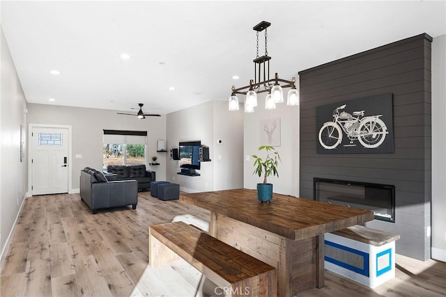 dining room featuring a large fireplace, baseboards, light wood-style floors, and recessed lighting