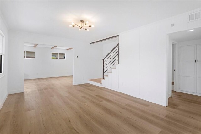 unfurnished living room featuring light wood finished floors, visible vents, baseboards, stairs, and a notable chandelier