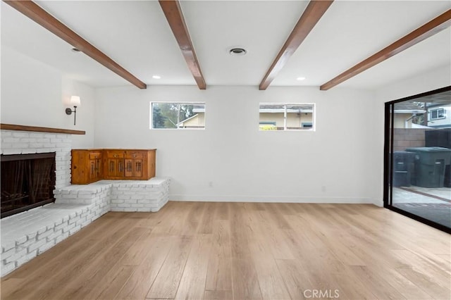 unfurnished living room with beamed ceiling, a brick fireplace, wood finished floors, and baseboards