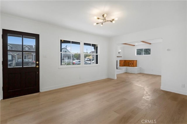 entrance foyer with a chandelier, baseboards, and light wood-style floors