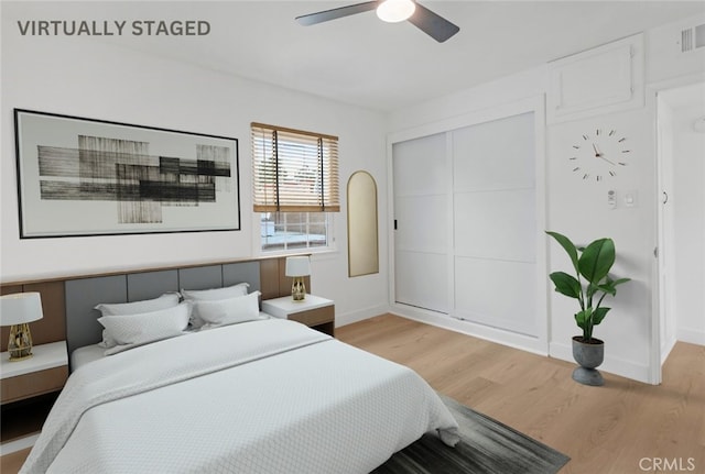 bedroom with a ceiling fan, visible vents, baseboards, light wood-style floors, and a closet