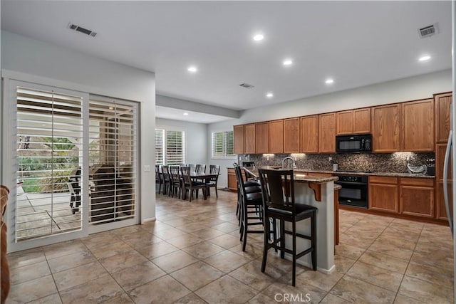 40467 Tiger Way, Palmdale, CA 93551 - kitchen featuring backsplash, black appliances, brown cabinets, and visible vents