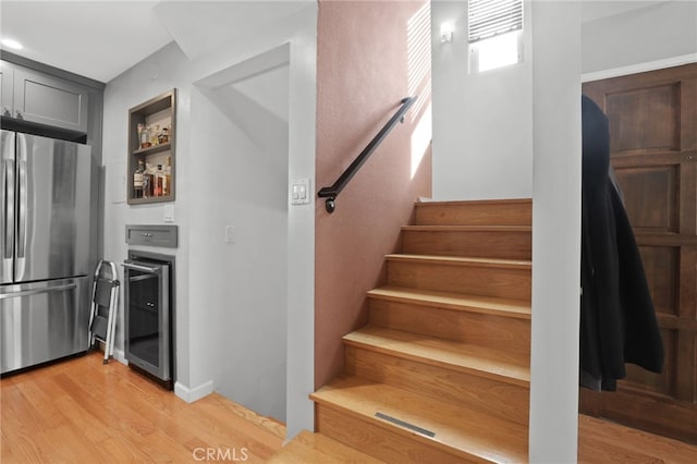 stairs featuring wine cooler, a dry bar, and wood finished floors