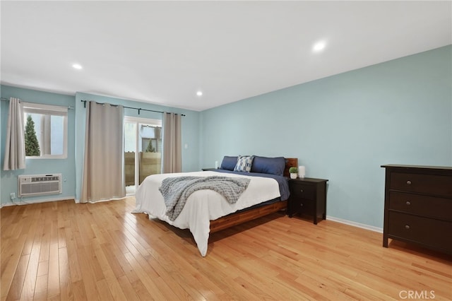 bedroom featuring a wall unit AC, baseboards, recessed lighting, light wood-style floors, and access to outside