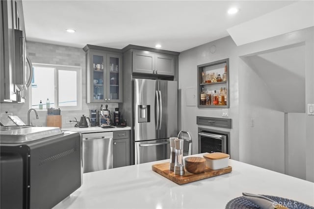 kitchen with recessed lighting, gray cabinets, light countertops, glass insert cabinets, and appliances with stainless steel finishes