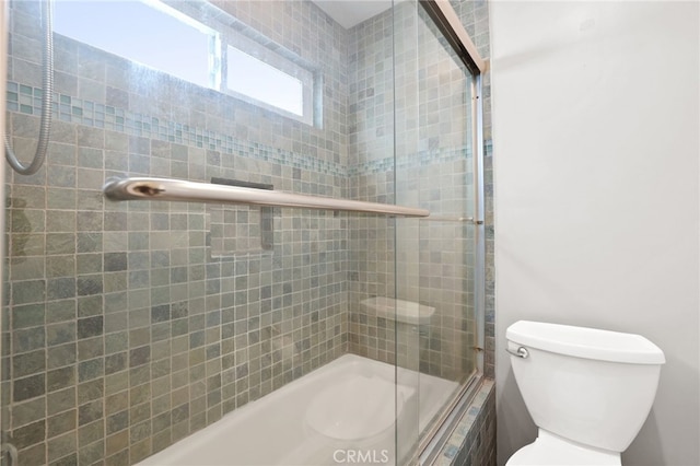 bathroom with tiled shower / bath combo and toilet