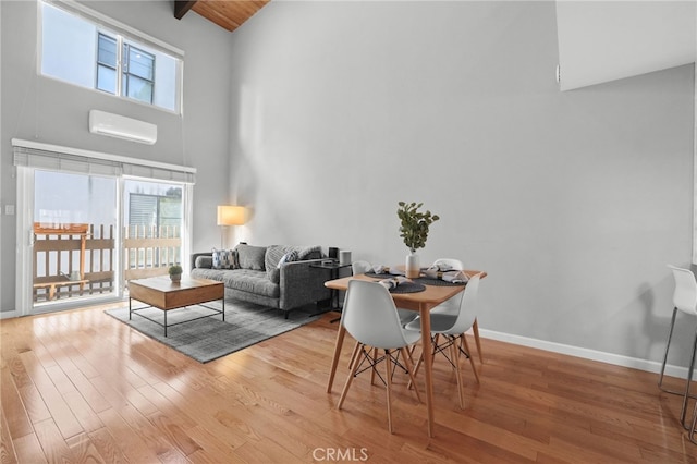 living area with an AC wall unit, wood finished floors, baseboards, and a healthy amount of sunlight