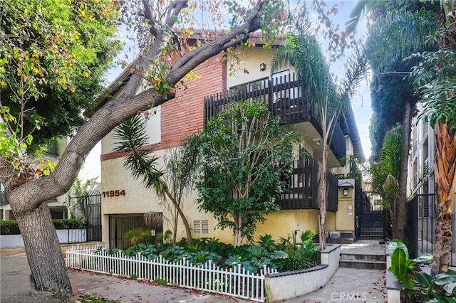 view of front of house with stairway, stucco siding, and fence