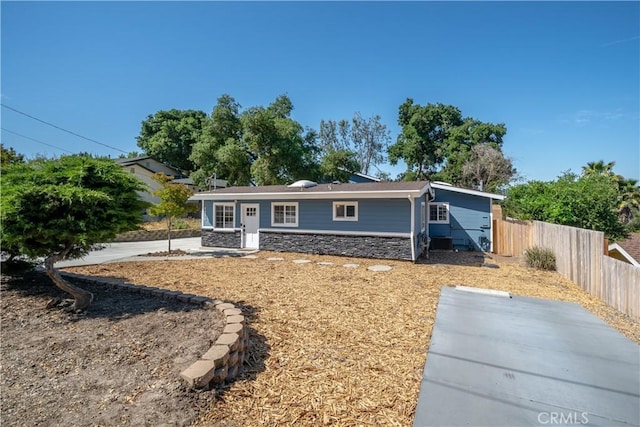 single story home featuring stone siding, a patio, and fence