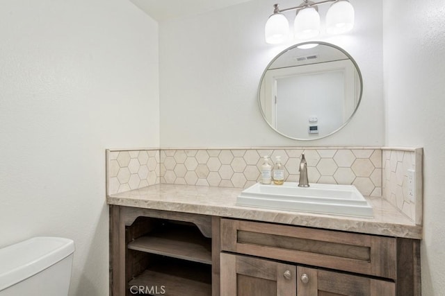 half bathroom featuring toilet, tasteful backsplash, visible vents, and vanity