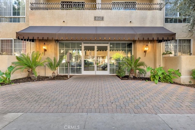 property entrance featuring a balcony and stucco siding