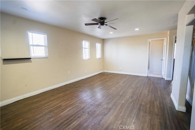 unfurnished room with a wealth of natural light, dark wood finished floors, and baseboards