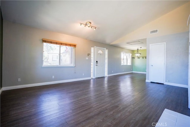 unfurnished living room with visible vents, dark wood-type flooring, attic access, vaulted ceiling, and baseboards