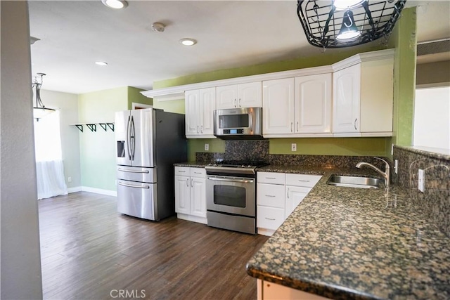 kitchen with dark wood-style flooring, stainless steel appliances, tasteful backsplash, white cabinets, and a sink