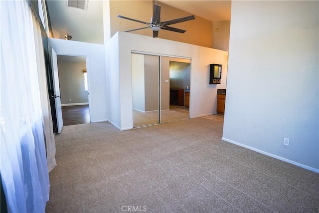 unfurnished bedroom with light carpet, baseboards, visible vents, high vaulted ceiling, and a closet