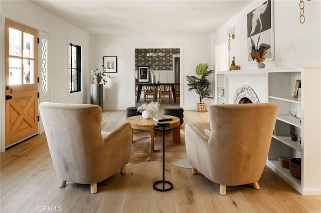 living area with a fireplace, light wood-style flooring, and baseboards