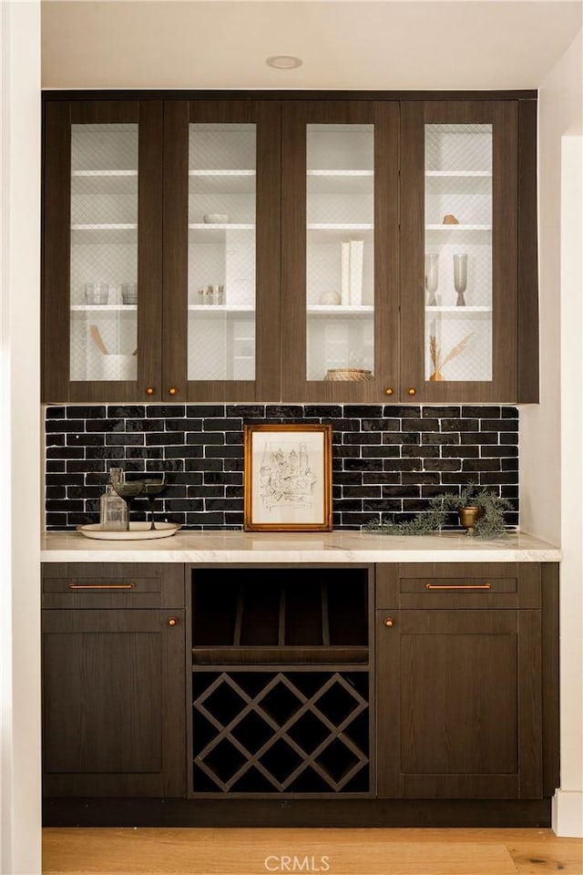 bar with light wood-style flooring, backsplash, and a dry bar