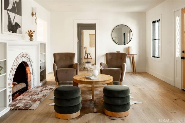 living area with light wood-type flooring, a fireplace, and baseboards