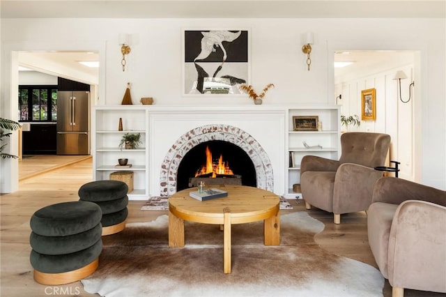 sitting room with a warm lit fireplace and wood finished floors