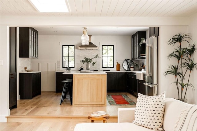 kitchen featuring a breakfast bar area, dark cabinets, high end refrigerator, light countertops, and beamed ceiling