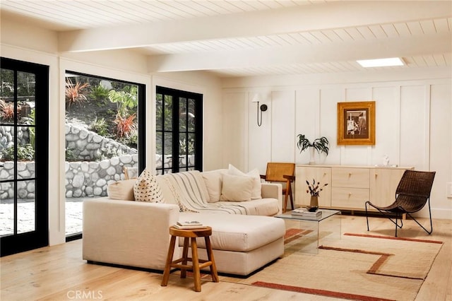 living area featuring wood ceiling, a decorative wall, beamed ceiling, and light wood finished floors