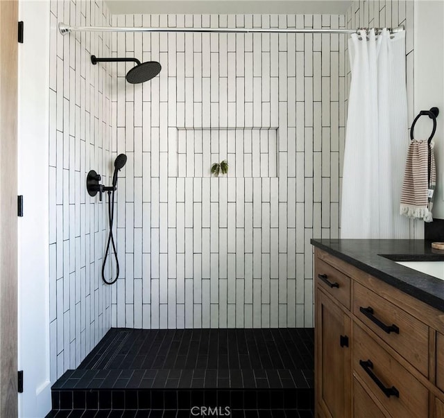 full bath with a tile shower and vanity