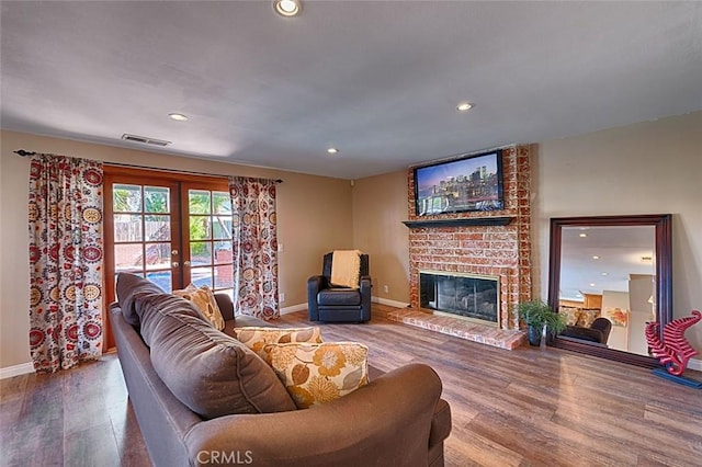 living area with visible vents, a brick fireplace, recessed lighting, french doors, and wood finished floors