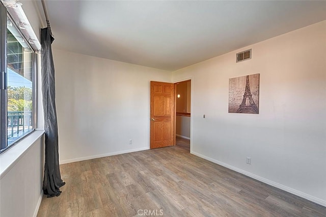 spare room with visible vents, baseboards, and wood finished floors